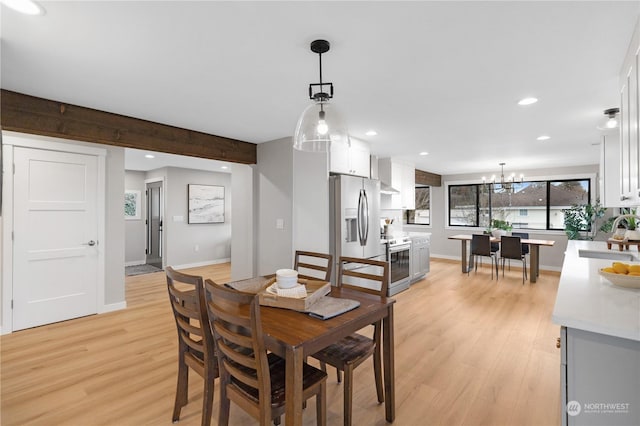 dining area featuring sink, beamed ceiling, a chandelier, and light hardwood / wood-style flooring