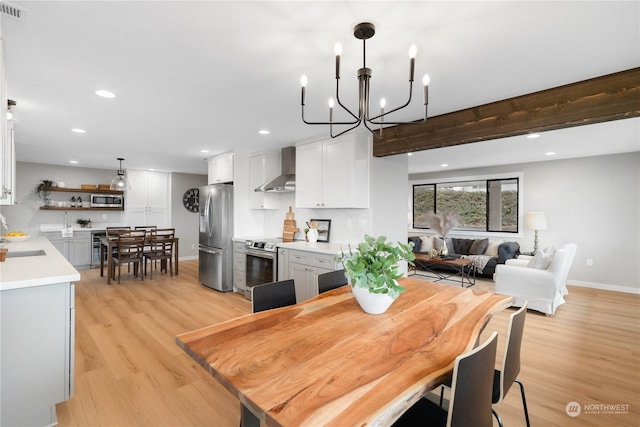 dining area featuring a chandelier, beam ceiling, light hardwood / wood-style floors, and sink