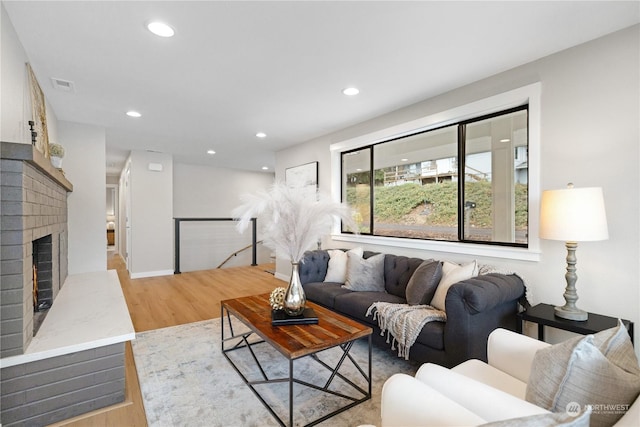 living room with light hardwood / wood-style floors and a brick fireplace