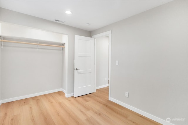 unfurnished bedroom with light wood-type flooring and a closet