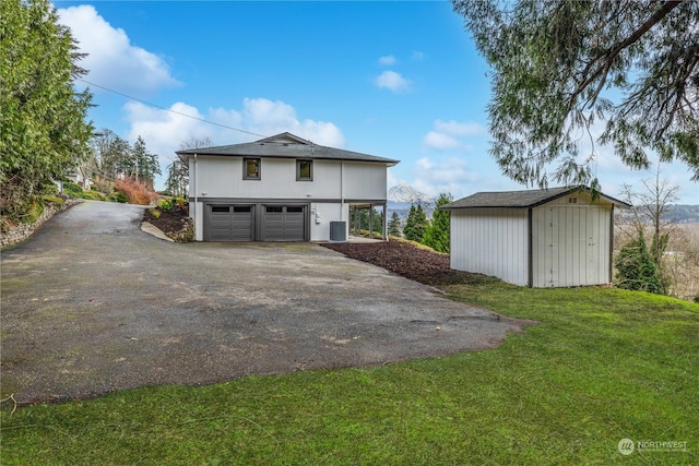 exterior space featuring central AC unit, a garage, a lawn, and a storage shed