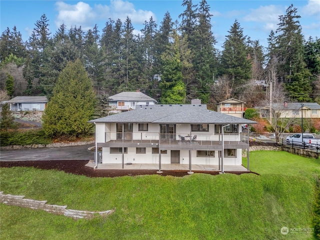 back of property featuring a yard, a balcony, and a patio