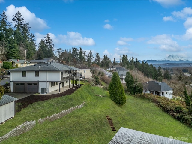 view of yard with a deck with mountain view, a garage, and central AC unit