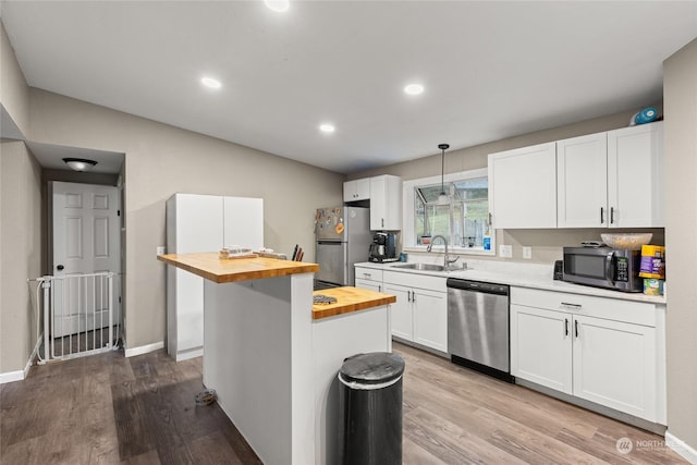 kitchen featuring sink, a kitchen island, wood counters, white cabinets, and appliances with stainless steel finishes