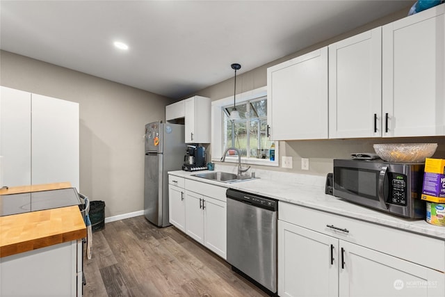 kitchen with dark wood-type flooring, hanging light fixtures, sink, appliances with stainless steel finishes, and white cabinetry