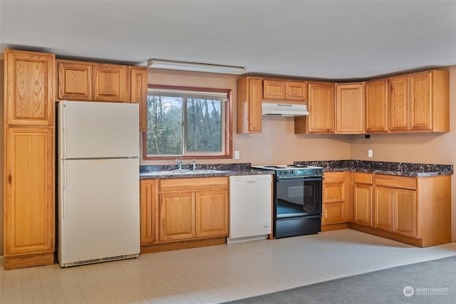 kitchen featuring white appliances, sink, and dark stone counters