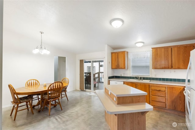 kitchen with sink, hanging light fixtures, a chandelier, white appliances, and a kitchen island