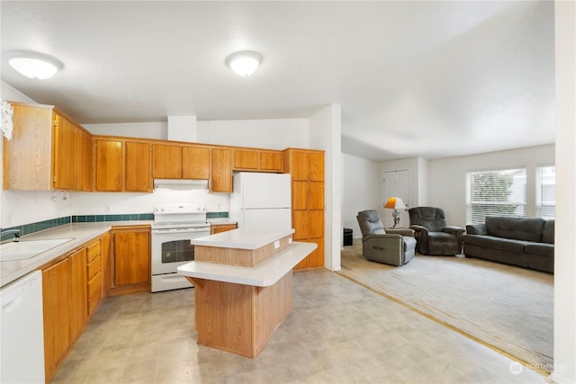 kitchen with a center island, white appliances, sink, vaulted ceiling, and light colored carpet