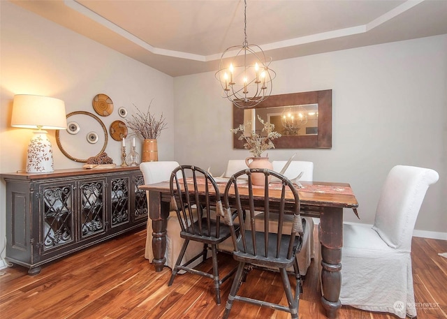 dining area with a raised ceiling, a chandelier, and dark hardwood / wood-style floors