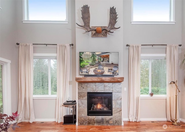 living room with a tile fireplace, a wealth of natural light, and a towering ceiling