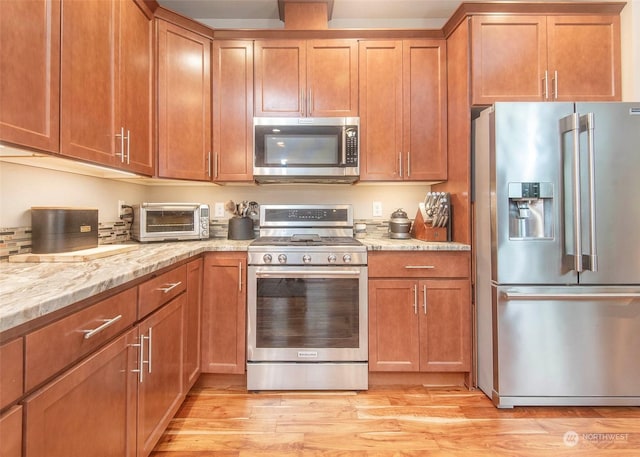 kitchen featuring stainless steel appliances, light stone counters, and light hardwood / wood-style flooring