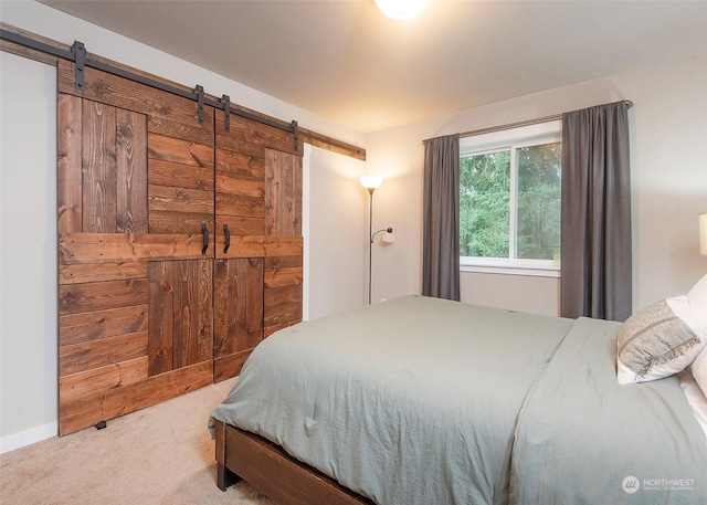 bedroom featuring a barn door and light colored carpet