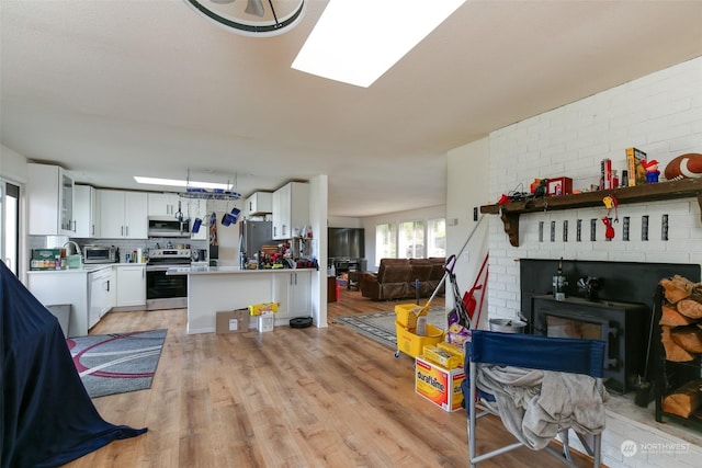 kitchen featuring white cabinetry, light wood-type flooring, appliances with stainless steel finishes, kitchen peninsula, and decorative backsplash