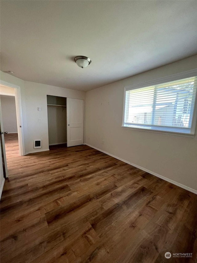 unfurnished bedroom with dark hardwood / wood-style floors and a closet