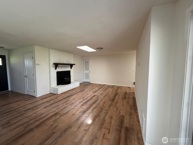 unfurnished living room featuring a skylight, baseboards, wood finished floors, and a fireplace