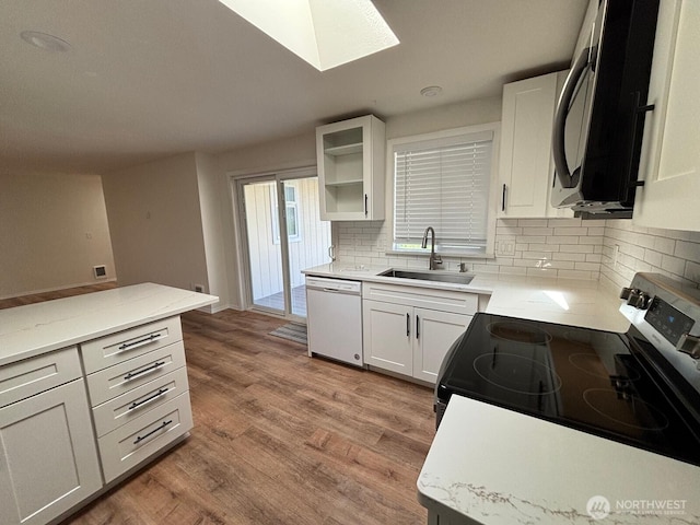 kitchen featuring tasteful backsplash, a sink, white dishwasher, electric range, and a skylight