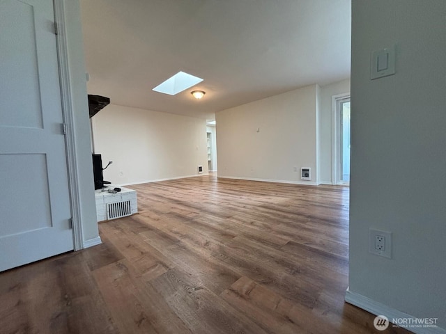 interior space featuring a skylight, wood finished floors, and baseboards