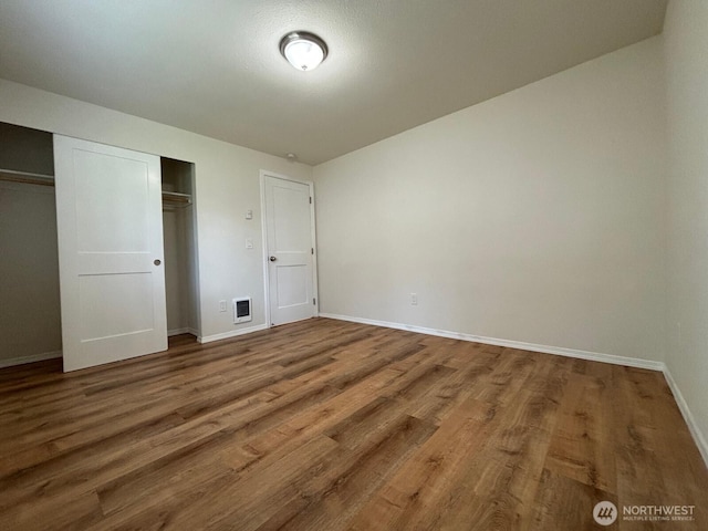 unfurnished bedroom with wood finished floors, a closet, and baseboards