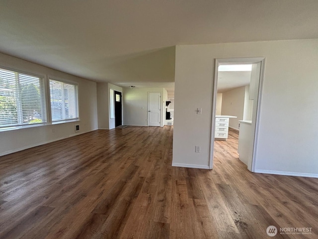 unfurnished living room featuring wood finished floors, visible vents, and baseboards