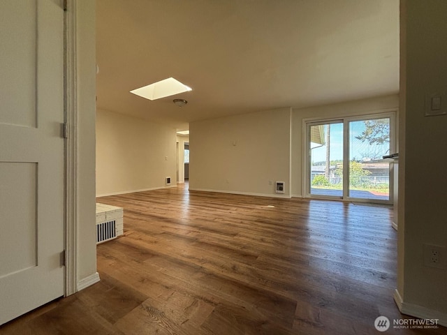 spare room featuring baseboards, a skylight, and wood finished floors