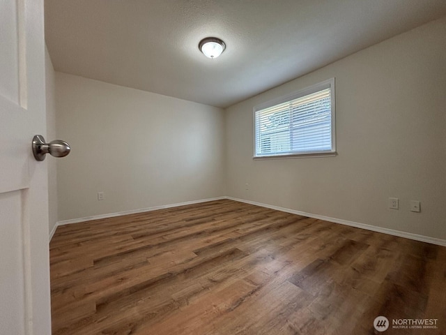 empty room with baseboards and wood finished floors