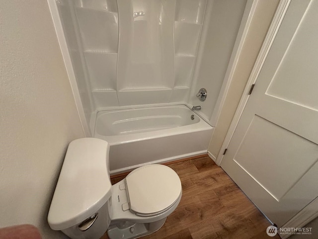 bathroom with wood finished floors, toilet, and shower / bathtub combination