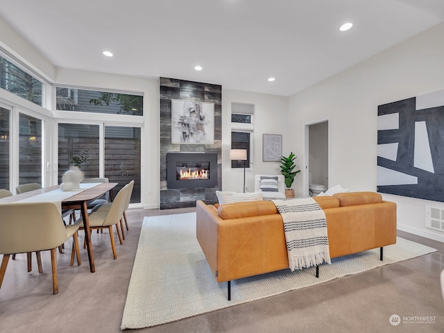 living room featuring a tile fireplace and concrete flooring