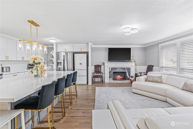 living room with wood-type flooring, ornamental molding, and a premium fireplace