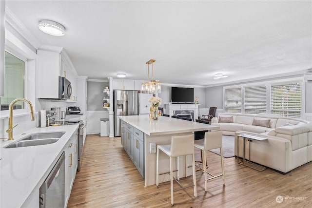 kitchen with white cabinetry, sink, a breakfast bar area, a kitchen island, and appliances with stainless steel finishes