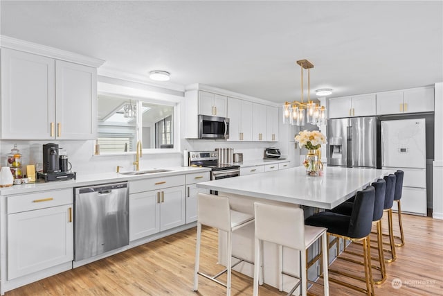 kitchen with appliances with stainless steel finishes, white cabinetry, a kitchen island, and sink