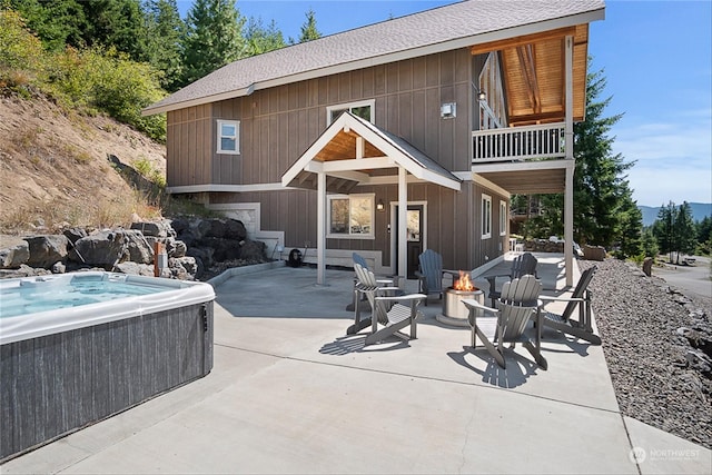 rear view of house featuring a hot tub, a balcony, a fire pit, and a patio area