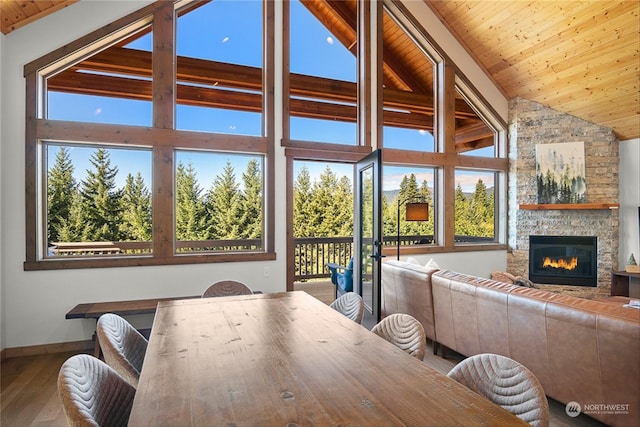 dining area with a fireplace, high vaulted ceiling, wood ceiling, and hardwood / wood-style flooring