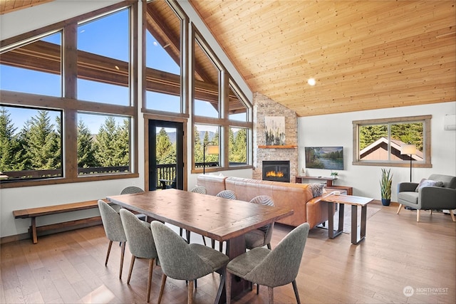 dining room with a wealth of natural light, wooden ceiling, a fireplace, and high vaulted ceiling