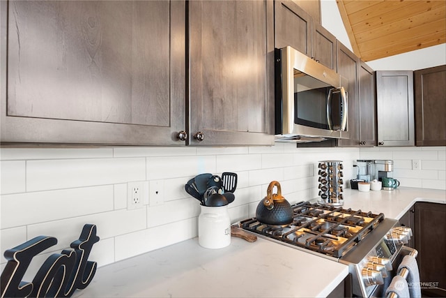 kitchen with dark brown cabinets, decorative backsplash, and vaulted ceiling