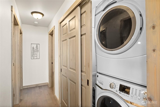 laundry room with hardwood / wood-style flooring and stacked washer and dryer