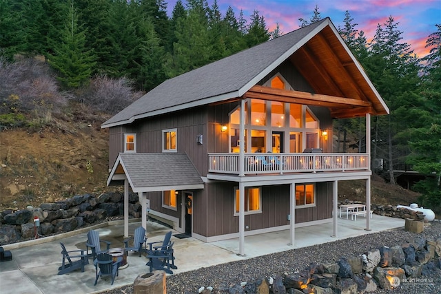 back house at dusk with a patio area, an outdoor fire pit, and a wooden deck