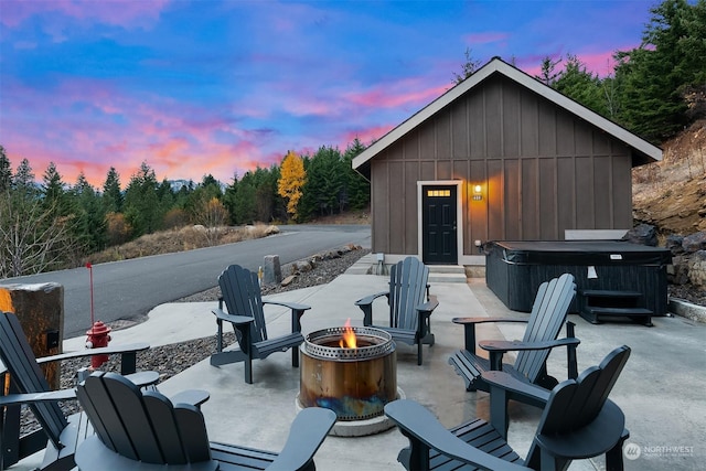 patio terrace at dusk featuring a hot tub and an outdoor fire pit