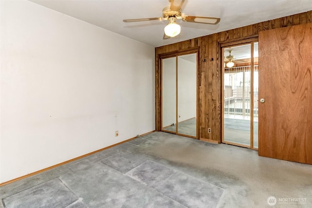 unfurnished bedroom featuring ceiling fan, light carpet, wood walls, baseboards, and access to exterior