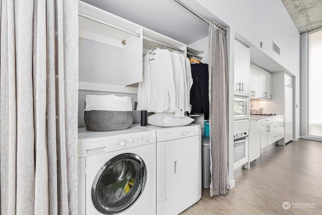 laundry room featuring washing machine and dryer and light hardwood / wood-style flooring