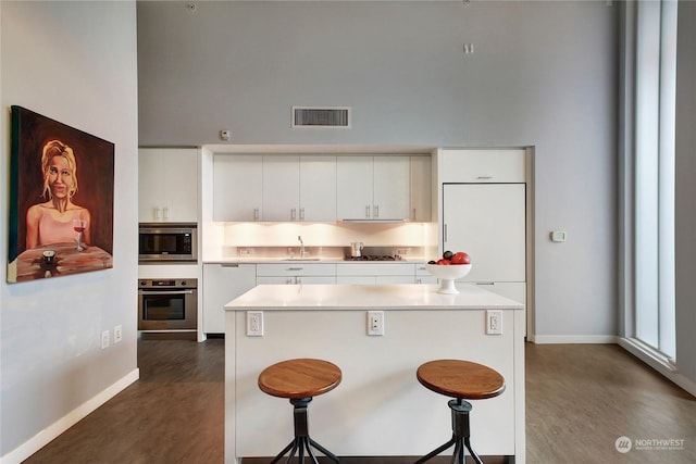 kitchen with white cabinetry, sink, a center island, a kitchen bar, and appliances with stainless steel finishes