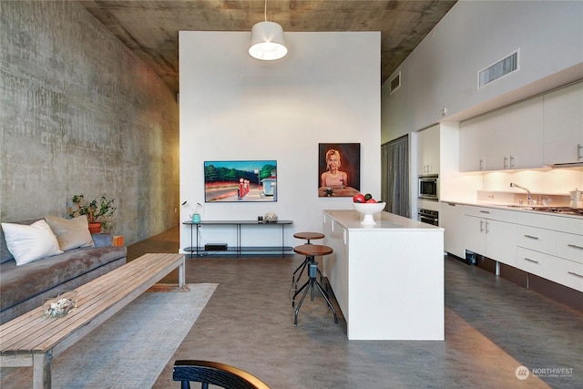 kitchen with white cabinetry, a center island, a kitchen breakfast bar, pendant lighting, and appliances with stainless steel finishes