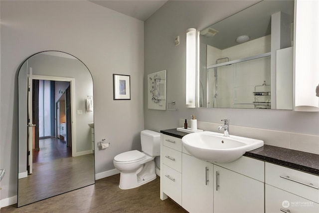 bathroom with wood-type flooring, vanity, a shower with shower door, and toilet