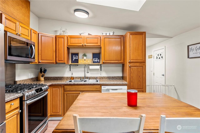 kitchen with sink, wooden counters, vaulted ceiling, and appliances with stainless steel finishes