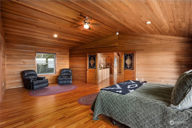 bedroom featuring vaulted ceiling, ceiling fan, hardwood / wood-style flooring, wood ceiling, and wooden walls