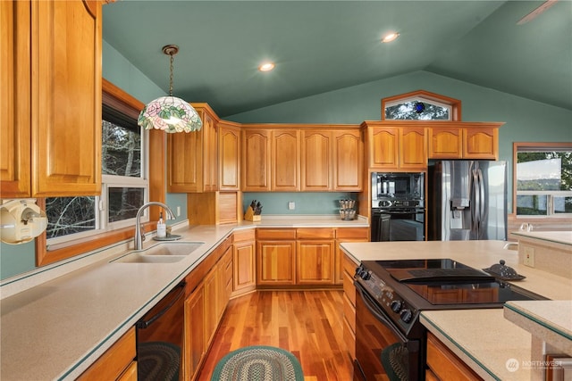 kitchen featuring light hardwood / wood-style flooring, sink, decorative light fixtures, black appliances, and lofted ceiling