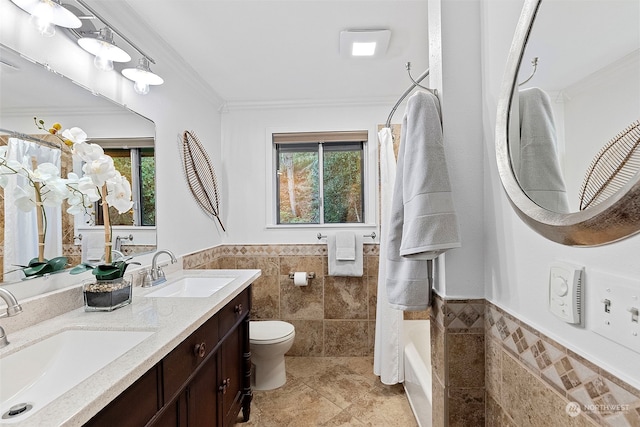 bathroom featuring toilet, plenty of natural light, tile walls, and a sink