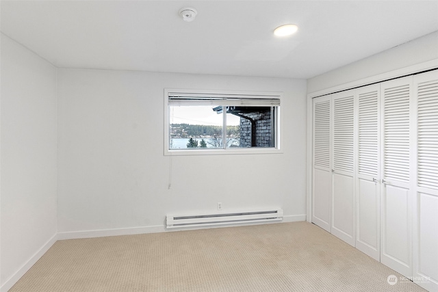 unfurnished bedroom featuring a baseboard heating unit, a closet, light carpet, and baseboards