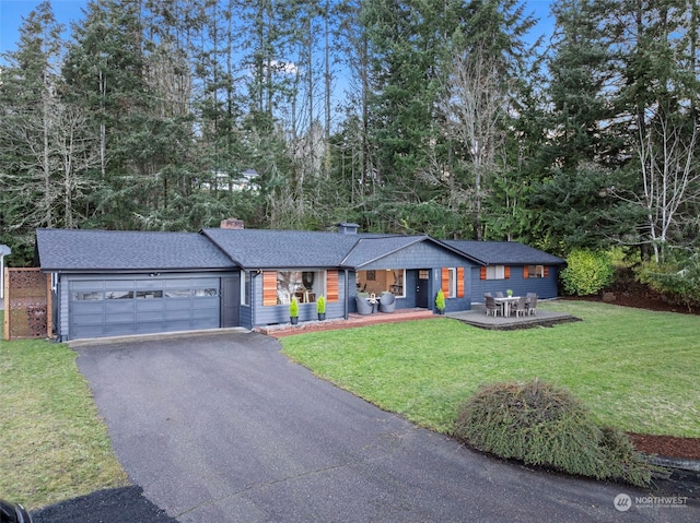 ranch-style home with aphalt driveway, a chimney, a patio area, a garage, and a front lawn