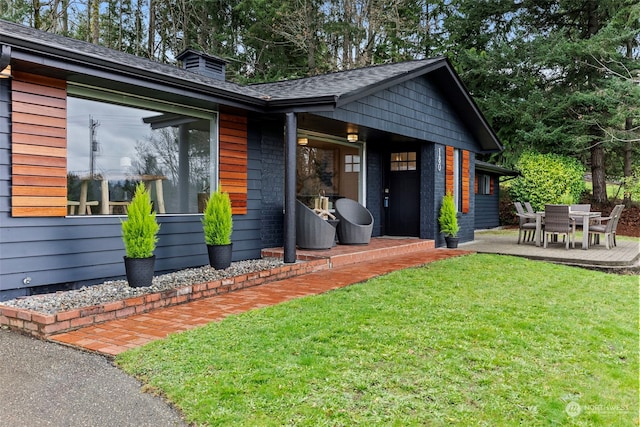 view of front of home with a patio, a front lawn, and roof with shingles