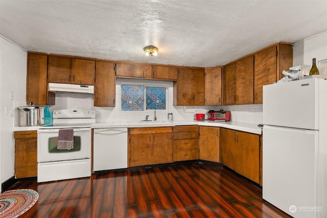 kitchen featuring sink, dark hardwood / wood-style flooring, a textured ceiling, white appliances, and decorative backsplash